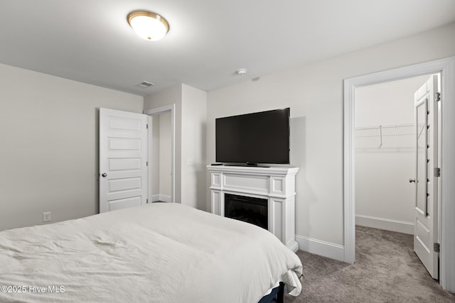 carpeted bedroom with a walk in closet and a closet