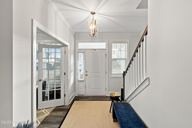 entryway with ornamental molding, dark hardwood / wood-style floors, and a chandelier