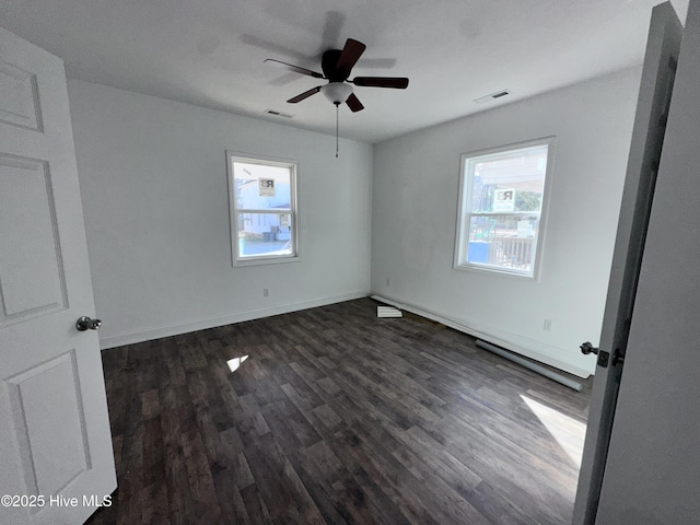 unfurnished bedroom with dark wood-style flooring, visible vents, baseboards, and multiple windows