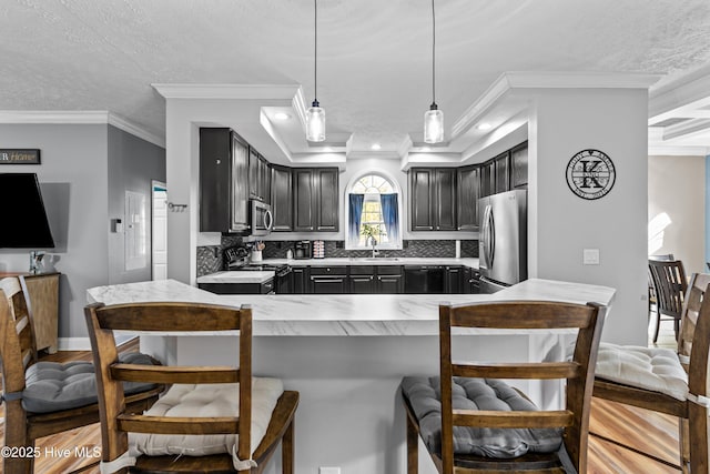 kitchen featuring pendant lighting, black appliances, decorative backsplash, ornamental molding, and kitchen peninsula