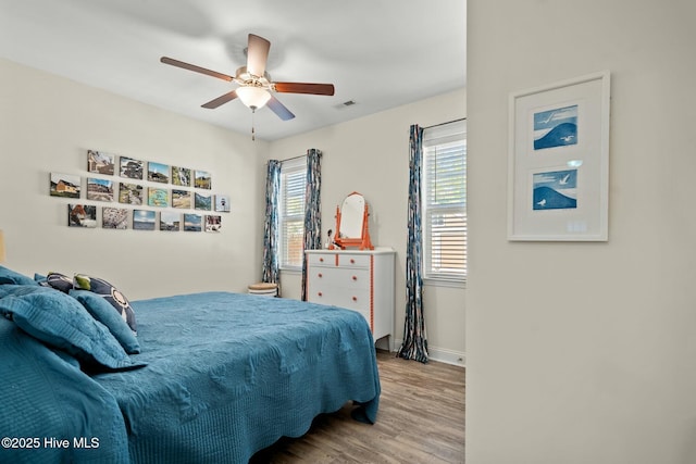 bedroom with ceiling fan, wood finished floors, visible vents, and baseboards