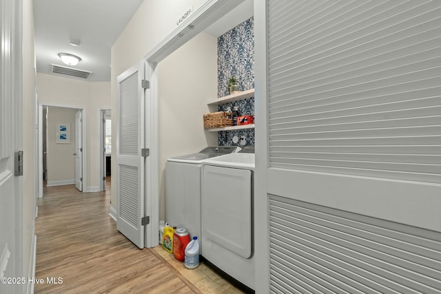 clothes washing area featuring laundry area, visible vents, washer and clothes dryer, and light wood-style floors