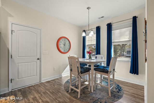 dining space featuring a chandelier, wood finished floors, visible vents, and baseboards