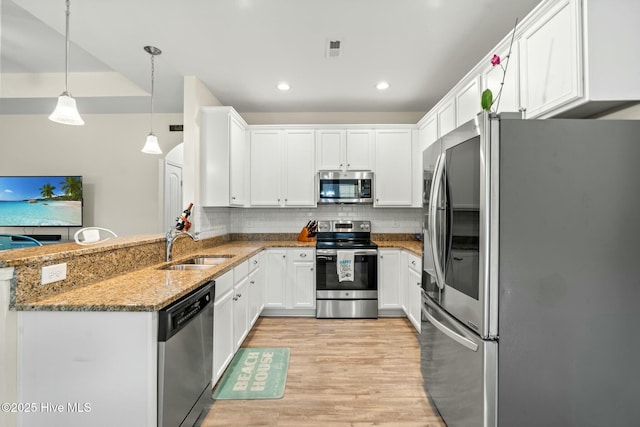 kitchen with tasteful backsplash, stainless steel appliances, stone counters, white cabinetry, and a sink