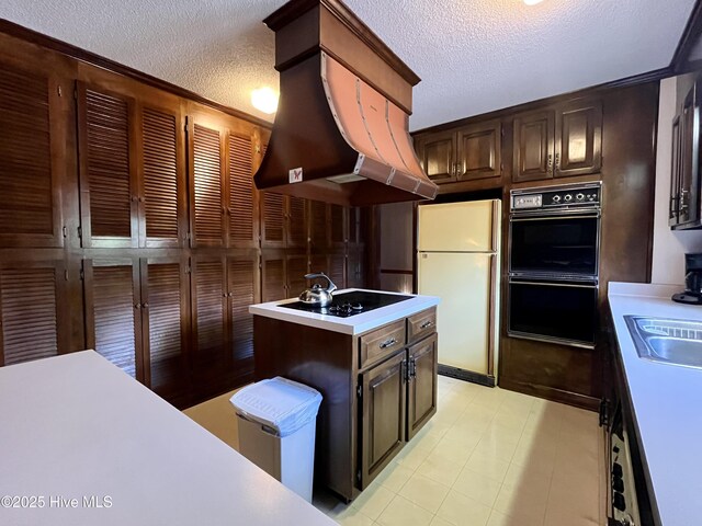 kitchen with dark brown cabinetry, a center island, a textured ceiling, island exhaust hood, and black appliances