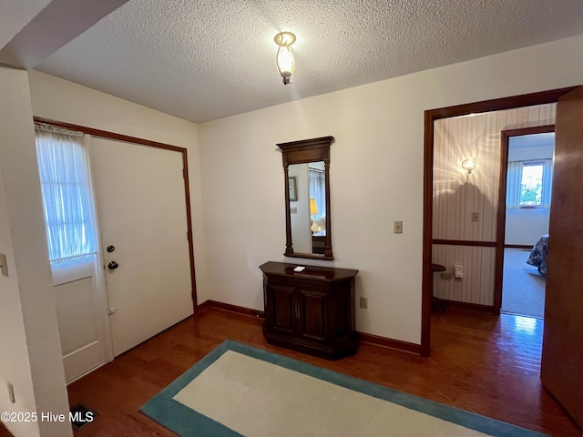 foyer entrance with dark wood-type flooring and a textured ceiling