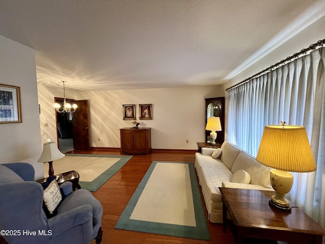 living room with a notable chandelier, dark hardwood / wood-style floors, and a textured ceiling