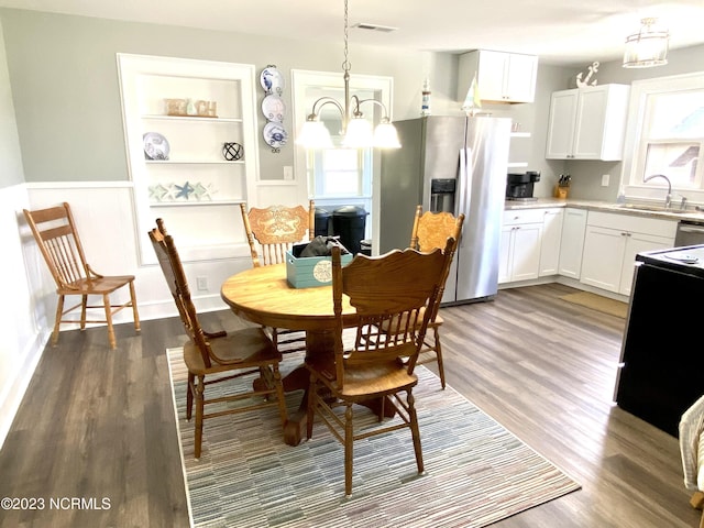 dining space featuring dark hardwood / wood-style flooring, sink, and an inviting chandelier