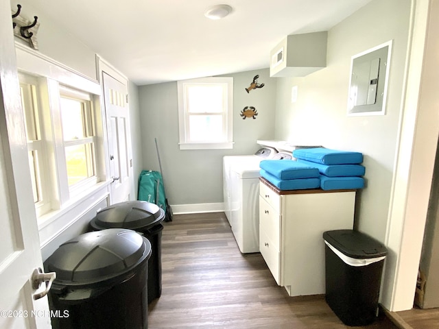 clothes washing area with separate washer and dryer, dark hardwood / wood-style floors, electric panel, and cabinets