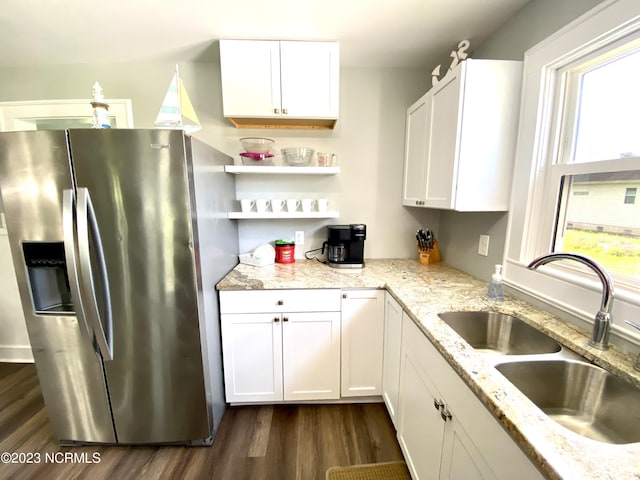 kitchen with white cabinetry, stainless steel refrigerator with ice dispenser, light stone countertops, and sink