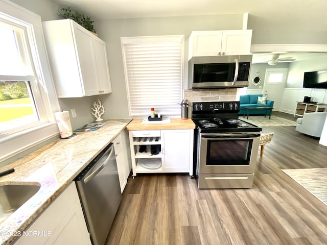 kitchen with stainless steel appliances, butcher block counters, white cabinets, and light hardwood / wood-style floors