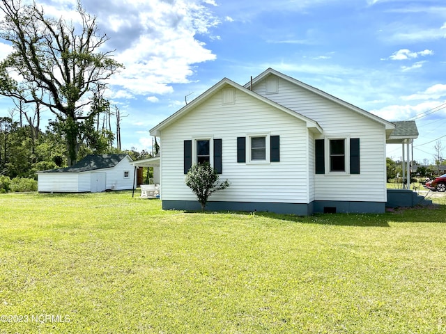 rear view of property featuring a yard and a storage unit