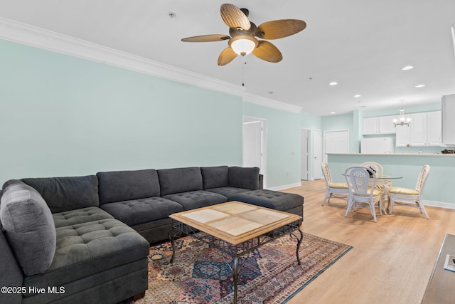 living room with ornamental molding, ceiling fan with notable chandelier, and light hardwood / wood-style floors