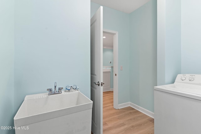 clothes washing area with washer / clothes dryer, light hardwood / wood-style flooring, and sink