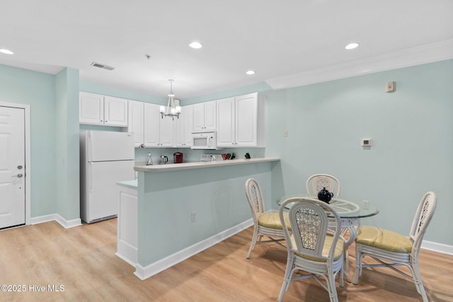 kitchen featuring pendant lighting, white appliances, white cabinets, kitchen peninsula, and light wood-type flooring