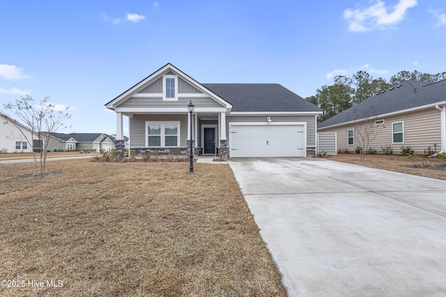 craftsman-style home with stone siding, a porch, concrete driveway, a front yard, and an attached garage