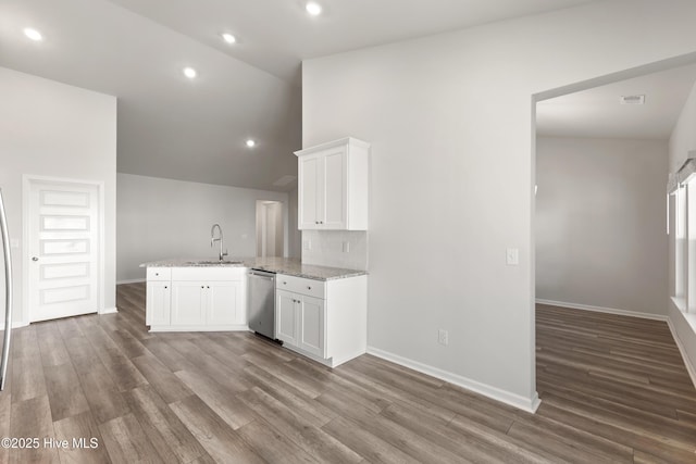 kitchen featuring wood finished floors, light stone countertops, white cabinetry, a peninsula, and stainless steel dishwasher