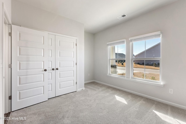 unfurnished bedroom featuring multiple windows, baseboards, a closet, and carpet floors