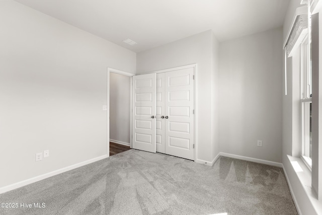 unfurnished bedroom with a closet, baseboards, and carpet