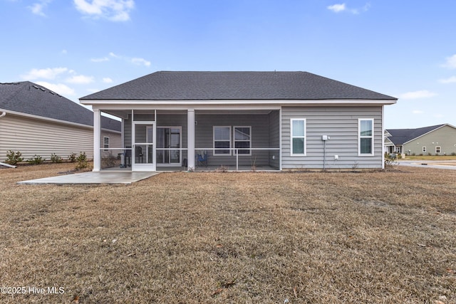 back of property with a sunroom, a lawn, a shingled roof, and a patio area