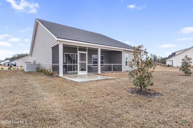 rear view of property featuring a patio area, a lawn, a sunroom, and roof with shingles