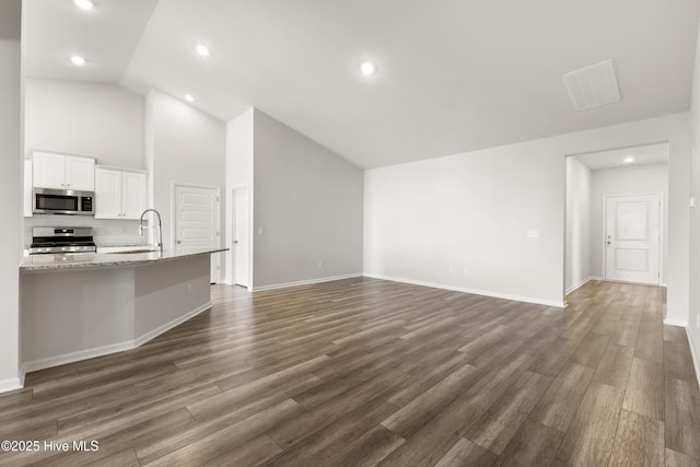 unfurnished living room with visible vents, baseboards, recessed lighting, a sink, and dark wood-type flooring