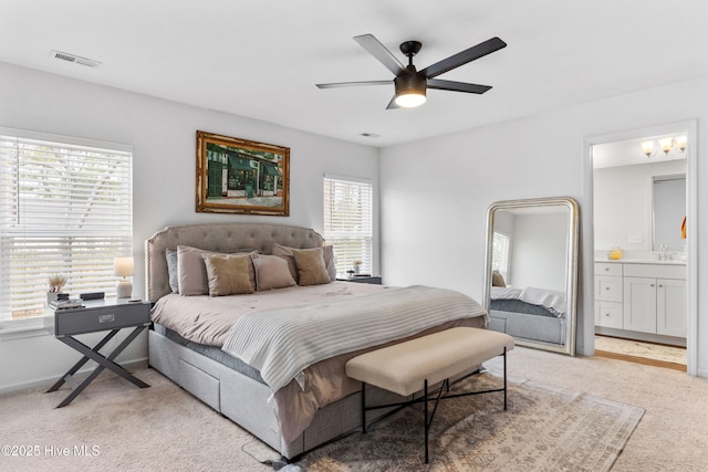 bedroom featuring sink, light colored carpet, ceiling fan, and ensuite bathroom