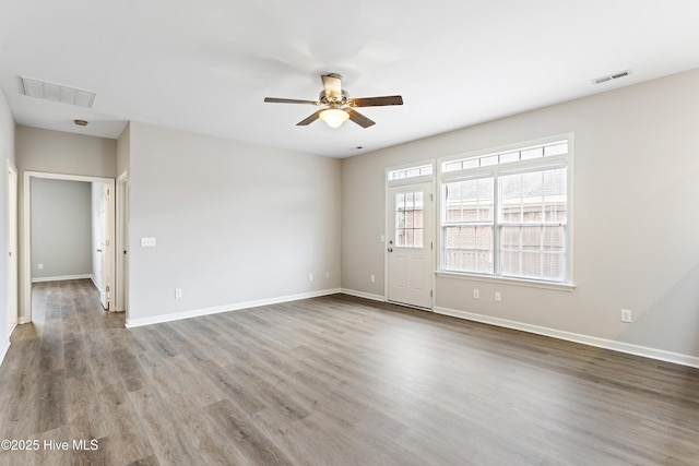 empty room with a ceiling fan, wood finished floors, and baseboards
