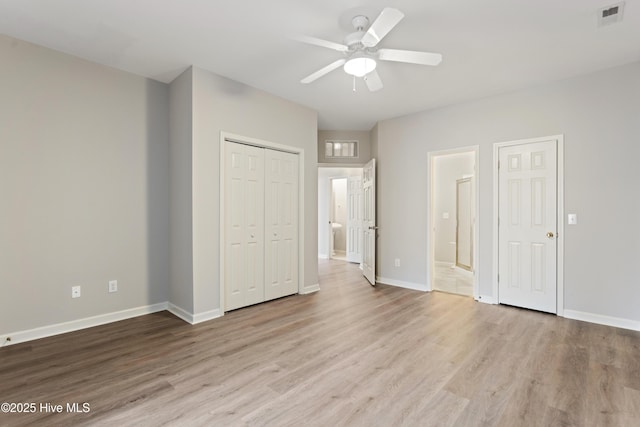 unfurnished bedroom featuring wood finished floors, baseboards, ensuite bathroom, a closet, and a ceiling fan