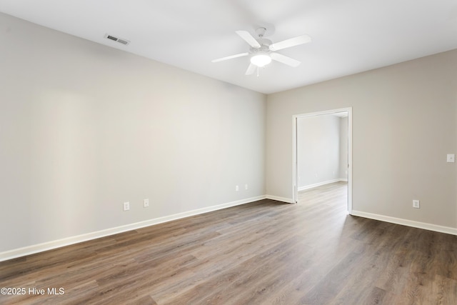 unfurnished room with wood finished floors, a ceiling fan, and baseboards