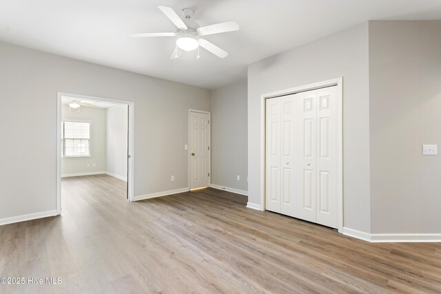 unfurnished bedroom featuring wood finished floors, baseboards, a closet, and ceiling fan