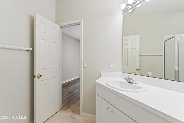 bathroom with vanity, baseboards, a shower with shower door, and tile patterned flooring