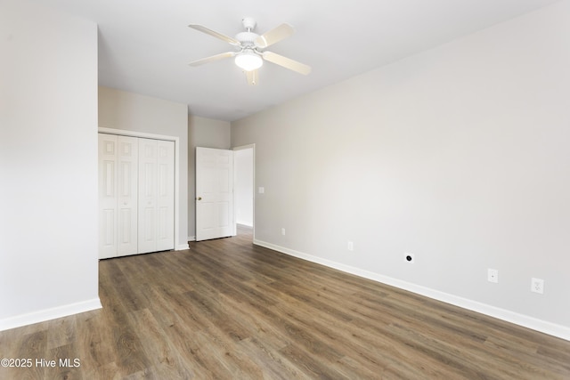 unfurnished bedroom featuring baseboards, wood finished floors, a closet, and ceiling fan