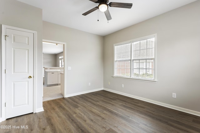 unfurnished room featuring ceiling fan, dark wood-type flooring, and baseboards