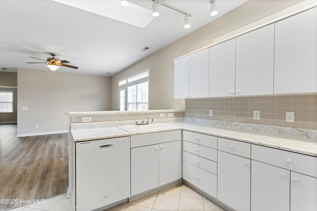 kitchen with dishwasher, a sink, a peninsula, and decorative backsplash