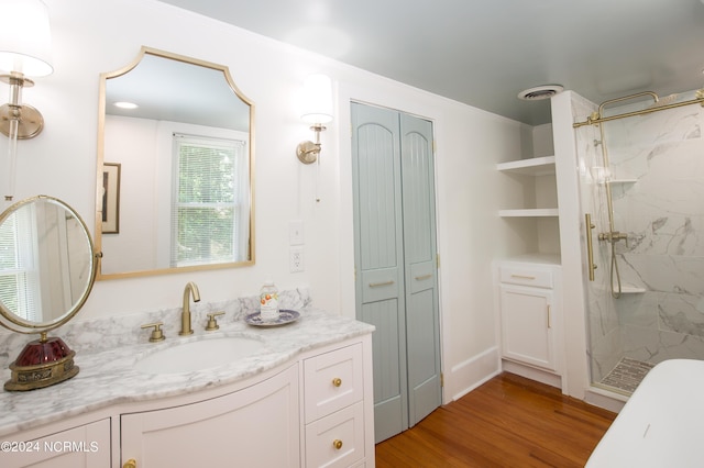 bathroom with hardwood / wood-style flooring, vanity, and a tile shower