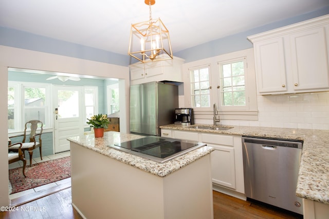 kitchen with sink, white cabinetry, hanging light fixtures, stainless steel appliances, and light stone countertops