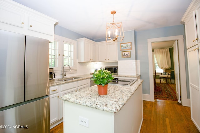 kitchen with sink, a center island, pendant lighting, stainless steel appliances, and white cabinets