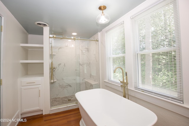 bathroom with hardwood / wood-style flooring and shower with separate bathtub