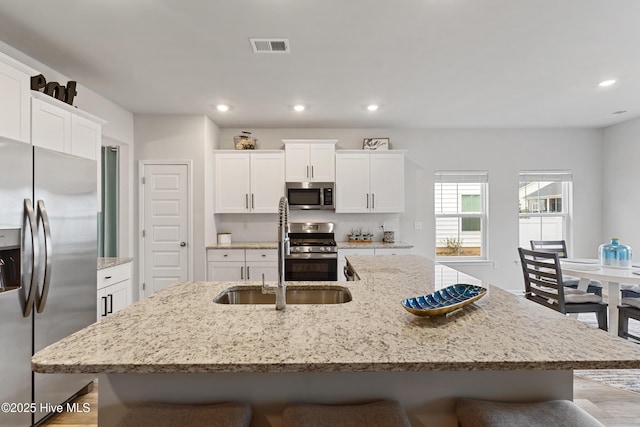 kitchen with stainless steel appliances, an island with sink, sink, and a kitchen breakfast bar