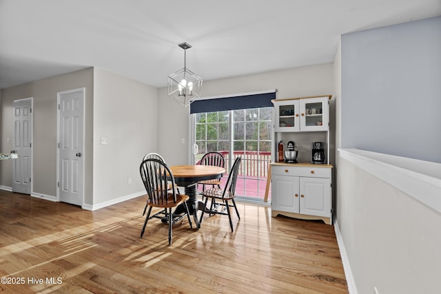 dining room with light wood finished floors, baseboards, and an inviting chandelier