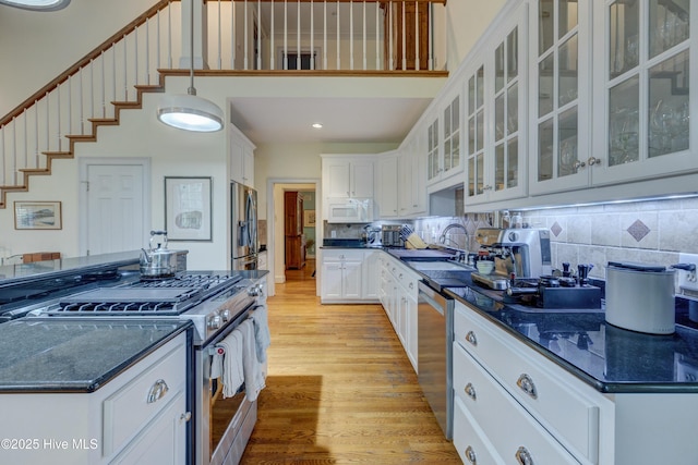 kitchen with tasteful backsplash, appliances with stainless steel finishes, light wood-type flooring, and white cabinets