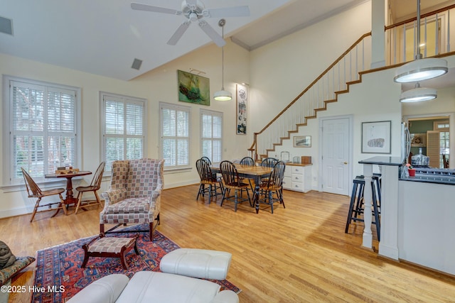 living room featuring ceiling fan, light hardwood / wood-style flooring, and a high ceiling