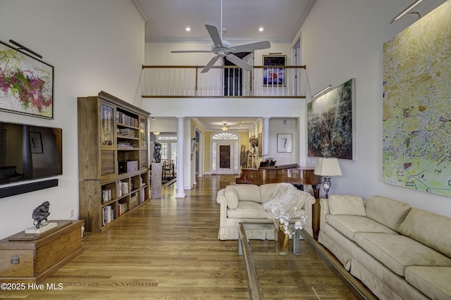 living room with ornate columns, crown molding, hardwood / wood-style flooring, and ceiling fan