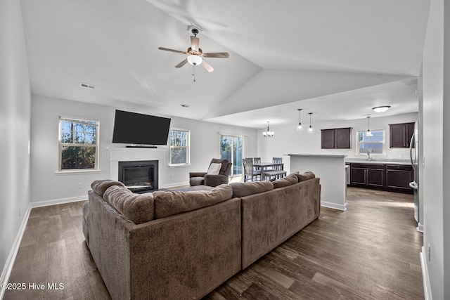 living room with ceiling fan with notable chandelier, sink, dark hardwood / wood-style flooring, and vaulted ceiling