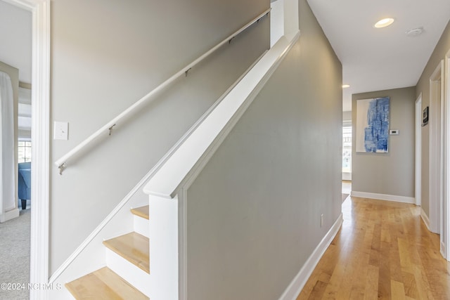 hallway featuring stairs, light wood finished floors, recessed lighting, and baseboards