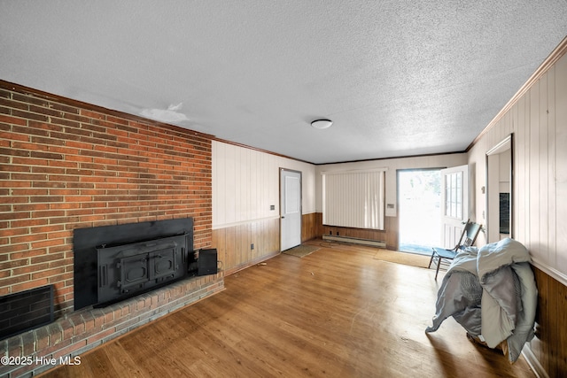 living room featuring crown molding, wood-type flooring, a textured ceiling, a baseboard radiator, and wooden walls