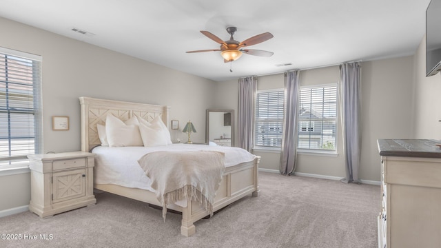 bedroom with multiple windows, light colored carpet, and ceiling fan