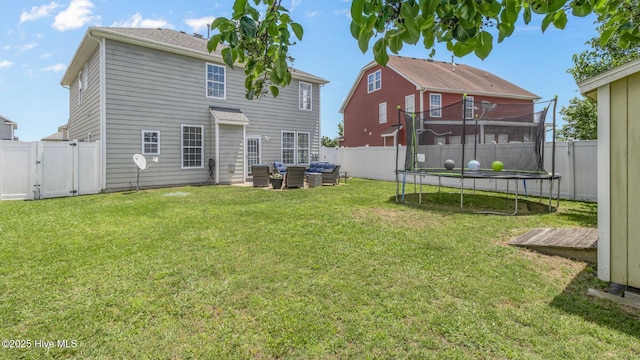 back of house with a trampoline, an outdoor living space, and a lawn