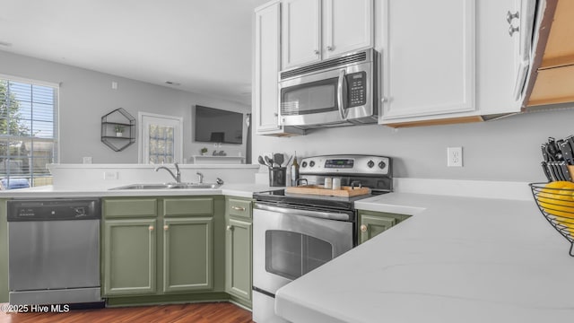 kitchen featuring sink, dark hardwood / wood-style flooring, green cabinets, stainless steel appliances, and white cabinets